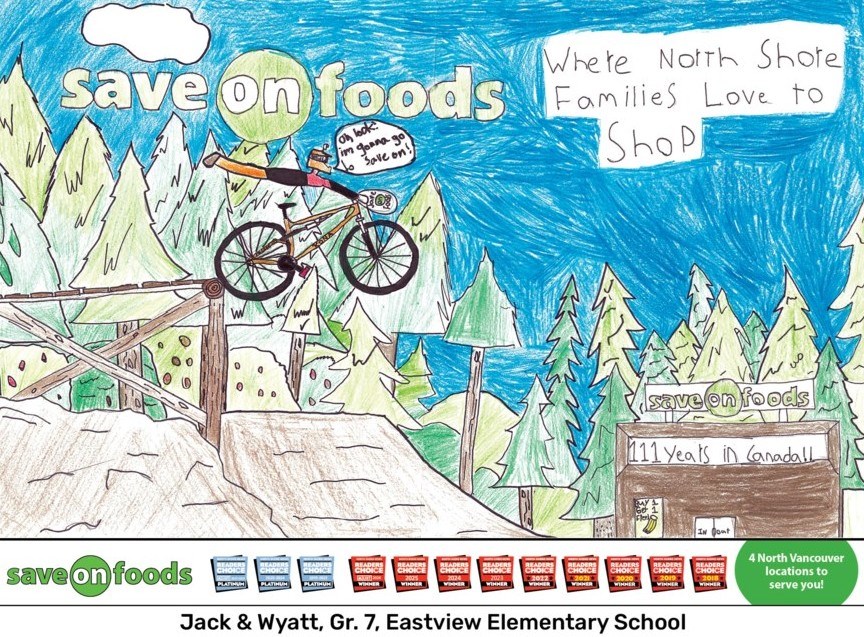 Colourful child-drawn outdoor scene with a mountain bike rider on a wooden trail surrounded by trees, with ocean and mountains in the background. Includes “Save-On-Foods” branding, text promoting North Shore families shopping there, and a sign referencing years in Canada. Bottom banner shows awards and attribution to Grade 7 students from Eastview Elementary.