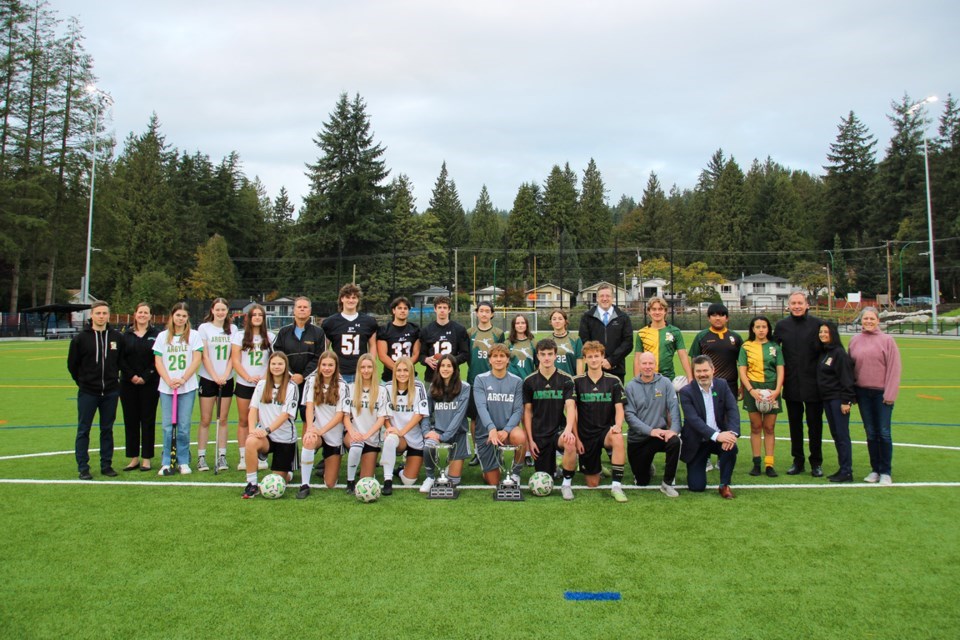 A large group photo of NVSD students, staff and the District mayor pose on an artifical turf field.