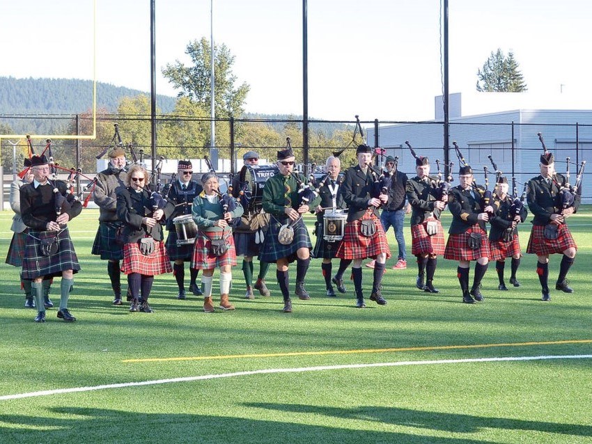 A group of bagpipers on an artificial turf field.