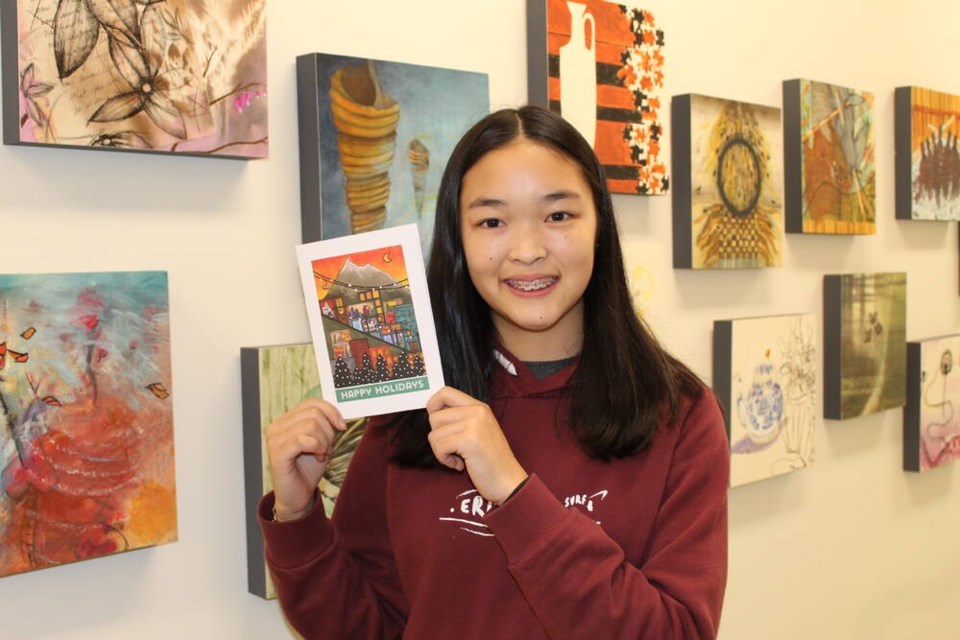 Lauren Yung poses holding a Christmas card.