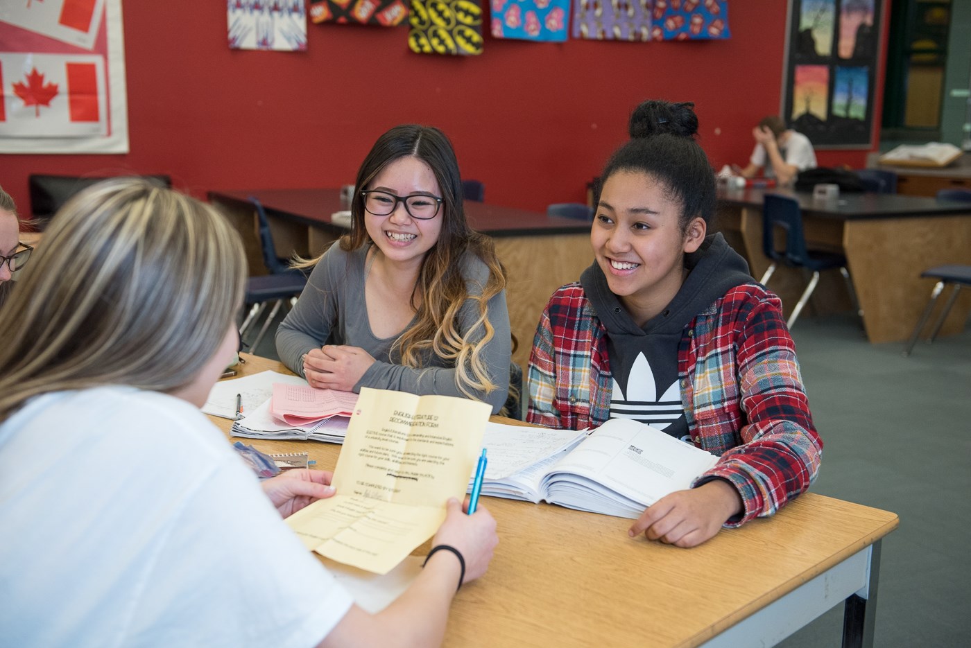 Three students smiling while studying with open books.